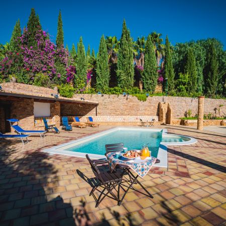 The pool area is surrounded by a stone wall and there is a roof with tiles where you can sit in the shade.