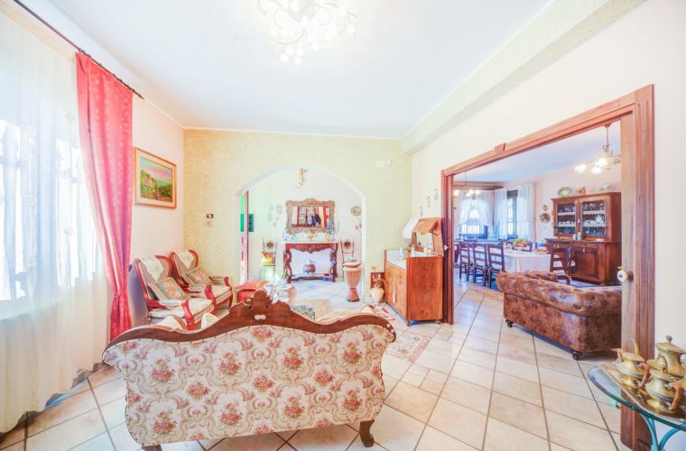 The main entrance leads directly into an open space with a large Sicilian rustic style kitchen, dining table and a living room with sofas, armchairs and television.