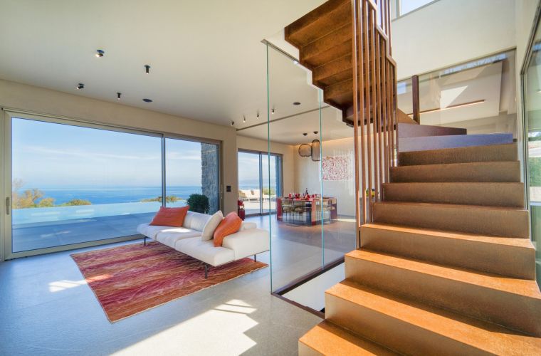 A designer staircase leads upstairs, where a tower-like sitting room, with its usual magnificent view, opens onto the terrace with a bar and sofas.