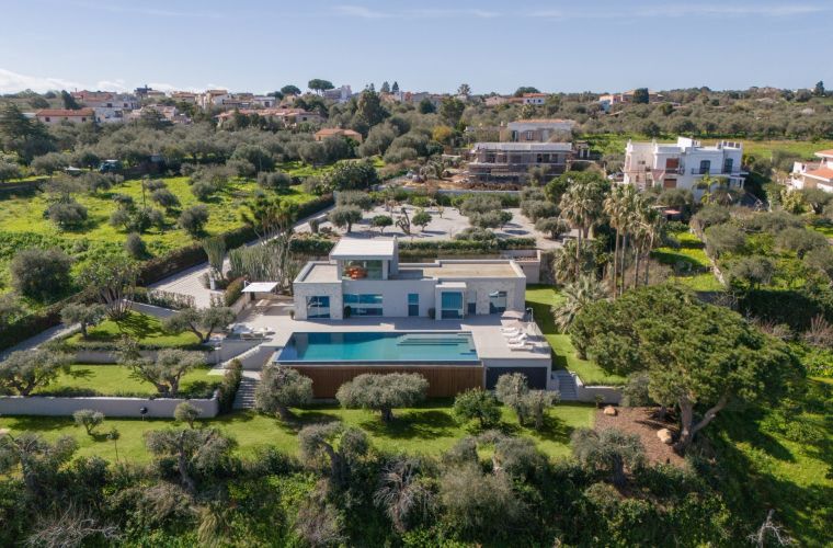 Mamma Luna Rossa is fully immersed in a Mediterranean garden with olive trees, palm trees, lawn and flowers.